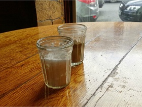 соль и перец в гранненых стаканах на деревянной поверхности круглого барного столика у окна классической рюмочной, бутербродной, закусочной СССР