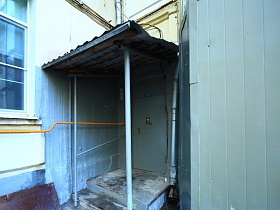небольшой деревянный порог с двумя ступенями под навесом подъезда 12 в углу жилого дома советского времени