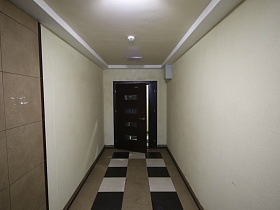 евроремонт в светлом коридоре на этаже с лифтом и входными дверьми в квартиру многоэтажного дома