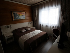 бежевые шторы и белая гардина на окне спальной комнаты в современном деревянном коттедже