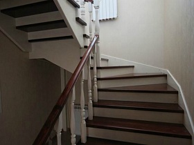бежевые стены у лестницы с коричневыми ступенями на второй этаж кирпичного двухэтажного дома