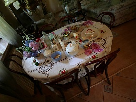 сервированный стол с цветами в вазочке на современной уютной даче в соснах