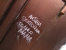 надпись, оставленная мелом на коричневых металлических входных дверях