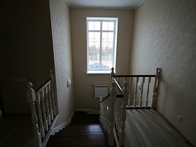 витая лестница с белыми перилами и коричневыми ступенями в двухэтажном кирпичном доме под съем