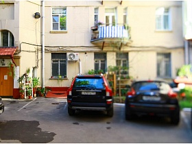 размеченные парковочные места во дворе дома с комнатными цветами на подоконниках,у входной двери и под навесом в подъезд на Долгоруковской