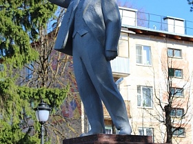 памятник Ленину в костюме, с протянутой вперед рукой и в полушаге на высоком гранитном постаменте в Сычево