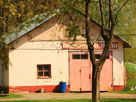 светлое здание "Пожарное депо" с синей круглой бочкой у розовых железных ворот, треугольной крышей на территории пожарной части ДФ