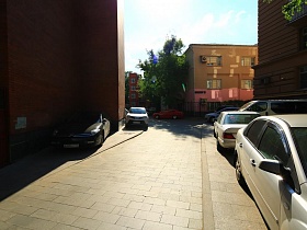 сочетание разнопланновых жилых домов в общем дворе с припаркованными машинами вдоль стен