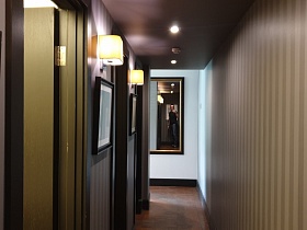 картины в коричневых рамках,прямоугольное зеркало на стенах длинного коридора с полосатыми обоями ресторана Академия