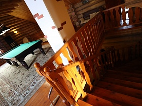 деревянная лестница с резными перилами  на втором этаже с бильярдной комнатой в доме из сруба