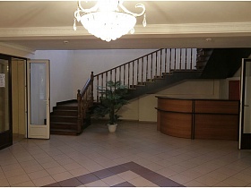 уголок администратора под лестницей в светлом холле дома отдыха