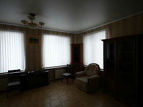 вертикальные белые жалюзи на окнах гостиной с бежевыми стенами и полом двухэтажного пустого дома в соснах под съем