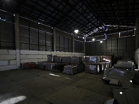 упакованные поддоны под поллиэтеленовой пленкой в два ряда на бетонном полу высокого металлического ангара на лофт территории бизнес-центра