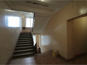 окрашенные светлые стены лестничной клетки с плиткой на полу на этажах жилого многоэтажного дома на Садовом