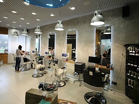 рабочи места парикмахера оснащены зеркалом, тумбой с ящиками и удобным креслом для клиента в модном салоне в торговом центре