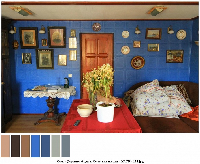 старинный деревянный столик на резной ножке покрытый вязанной салфеткой, угловой мягкий коричневый диван у голубой стены со старинными портретами в рамках и картинами в одной из комнат сельского дома