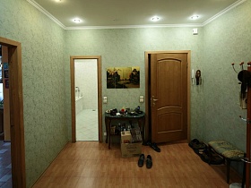 напольная вешалка, небольшая скамейка и обувь на коврике за входной дверью в трехкомнатную квартиру № 16