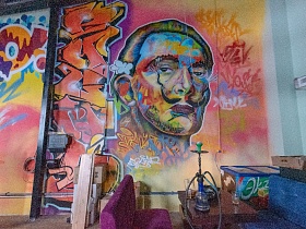 разноцветные диваны вокруг стола с кальяном у стены с красочным граффити молодежного ночного клуба лофт