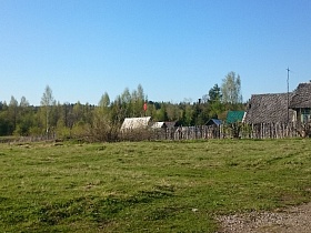 жилой дом с хозяйственными постройками на участке за деревянным забором на краю старой деревни 2