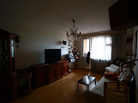 мебельная стенка, мягкая мебель на полу с коричневым линолеумом в светлой гостиной актерской трехкомнатной квартиры