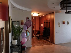гелиевые разноцветные шары у стеклянных шкафов в светлой студии с винтовой лестницей стильной квартиры бухгалтера