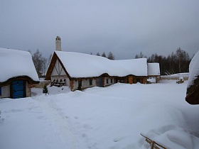 огромные сугробы снега на территории ресторана, стилизованного под хутор в коттеджном поселке