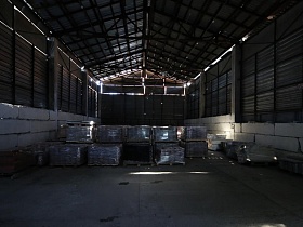 стопки упакованных поддонов на бетонном полу металлического ангара на лофт территории бизнес - центра