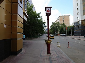 фонарный столб на тротуаре, выложенном плиткой, на перекрестке улиц напротив современного красивого здания "Казино"