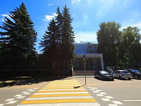 желтая зебра на двухполосной автомобильной дороге с указателем пешеходного перехода перед зданием современной гостиницы "Дубна" времен СССР