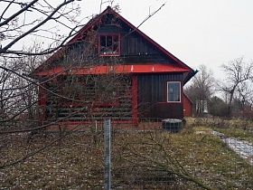 металлическая сетка с высокими воротами вдоль зимнего участка с деревянным домиком в деревне