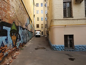 яркое и красочное граффити на стене жилого дома в узком витиеватом дворе в центре столицы для съемок кино