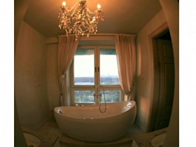 вид на белую ванну у окна со шторами