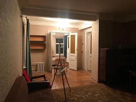 две пустых книжных полки на бежевой стене над секциями отопительной системы в смежной комнате с гостиной с открытыми дверьми в разные комнаты квартиры на Остоженке
