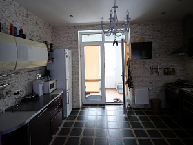 открытая дверь в кухню  коричневого цвета у стены кирпичной кладки