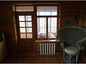 оригинально серое круглое сетчатое кресло с большой спинкой в углу спальной комнаты с отопительной системой под окном и входной дверью деревянной дачи музыканта