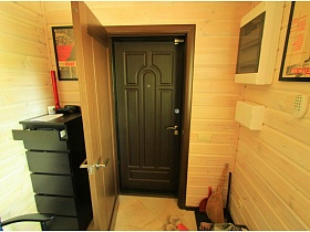 черный высокий комод у входа в прихожую с двойной дверью на современной деревянной даче работника кино