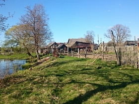 деревянный дом с хозяйственными постройками и просторным загоном для лошадей на берегу неширокой речушки в старой деревне 2