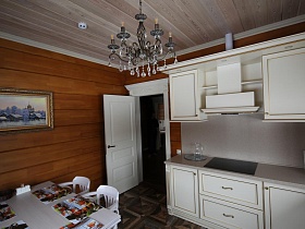 большая люстра, стилизованная под свечи на деревянном потолке кухни съемного коттеджа
