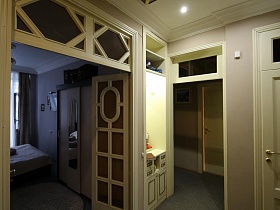 большой светлый шкаф для одежды в углу спальни за филенчатой межкомнатной дверью