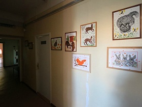 картины с детскими работами на стене у белой двери