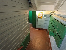 зеленые почтовые ящики на стене общего коридора на первом этаже в подъезде сталинки