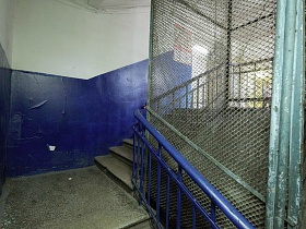 синие панели на стенах лестничной площадки в коммунальном общежитии