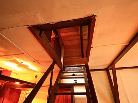 деревянная лестница на второй этаж под крышей в небольшом жилом домике у пруда