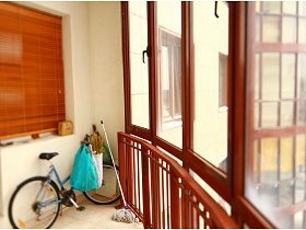 дамский велосипед, пакеты, швабра на светлом полу просторной мансарды с большими окнами на всю стену простой квартиры с восточной спальней