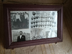 коричневая рамка с фотографиями прошлых лет под стеклом на стене деревянного дома заброшенной деревни