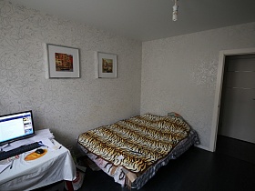 тигровое покрывало на большой кровати в светлой спальне с белым потолком и темно серым полом современной квартиры на первом этаже