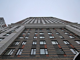 вид снизу на темно серый фасад в нише светло серого многоэтажного жилого дома