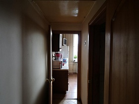 телевизор на холодильнике у окна на кухне через открытую дверь из узкого коридора квартиры сталинки