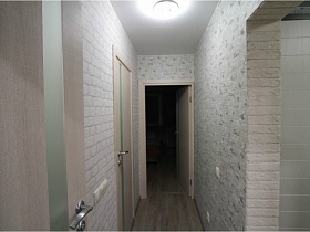 серебристая ручка на межкомнатных дверях в коридоре с серыми обоями в семейной новостройке