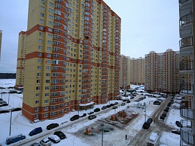 придомовая территория с детской площадкой и многочисленными машинами у дорог к высотным зданиям в Новострое